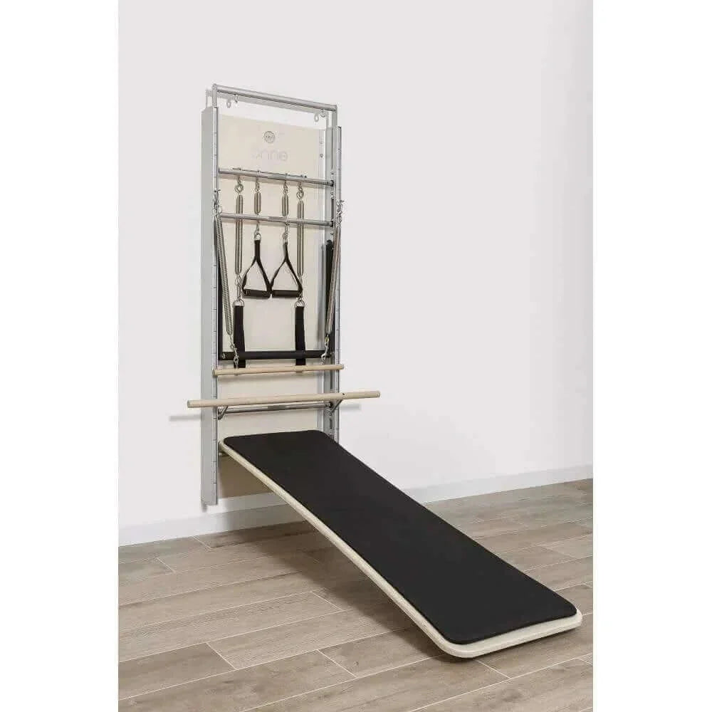 Pilates Wall Unit 5-en-1 vue latérale avec plateforme inclinée noire et sangles de suspension sur cadre aluminium brossé