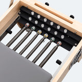 Vue de dessus de cinq ressorts torsadés de différentes couleurs, résistance, rail noir, rouleaux de guidage pour reformer Pilates