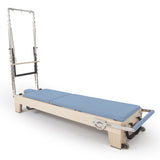 Reformer Pilates Elite en bois clair avec coussins bleu ciel et système de poulies chromées