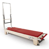 Reformer Pilates Elite en bois clair avec coussins rouge vif et cadre métallique chromé